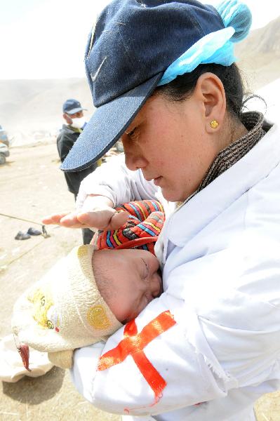 A nurse of a medical team wipes away tears on a baby in the Tibetan Autonomous Prefecture of Yushu, northwest China's Qinghai Province, April 18, 2010. 