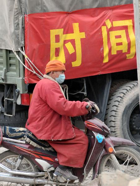 A monk rides a motorcycle past the truck transporting relief supplies in Gyegu Town, the quake-hit Tibetan Autonomous Prefecture of Yushu, in northwest China&apos;s Qinghai Province, April 17, 2010. The 7.1-magnitude earthquake that struck Yushu of Qinghai Province, left 1,484 dead and 312 still missing, and about 100,000 people were relocated.