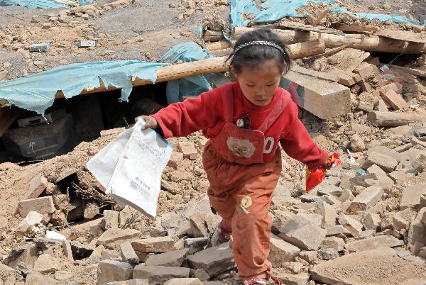One of the daughters of Ngot (transliterated) finds a textbook from the debris in Gyegu Town of the Tibetan Autonomous Prefecture of Yushu, northwest China&apos;s Qinghai Province, April 17, 2010. Ngot, a 45-year-old man living in Gyegu Town, lost his wife in the fatal earthquake that struck here early Wednesday. He planned to do business in the future to raise his six daughters, aged from one and a half to 15. 
