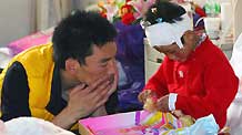 A volunteer (L) plays with an injured child at the 1st affiliated hospital of Xi'an Jiaotong University in Xi'an, northwest China's Shannxi province, April 18, 2010. Many volunteers of the Tibetan ethnic group supplied oral interpretation service in hospitals in Xi'an, where injured people from the quake-hit Yushu Tibetan Autonomous Prefecture of northwest China's Qinghai Province are treated.