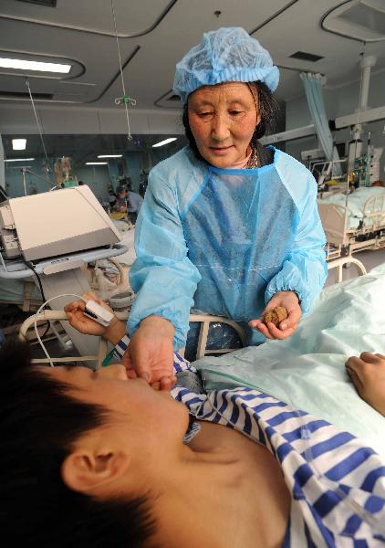 Tibetan volunteer Cering feeds food to an injured at the Huaxi Hospital Affiliated to Sichuan University in Chengdu, southwest China&apos;s Sichuan Province, April 18, 2010. Cering came from Ganzi Tibetan Autonomous Prefecture of Sichuan Province to the hospital and offered assistance to the injured people.