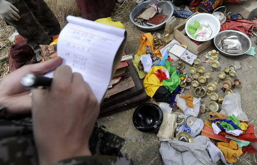 A man takes note of items dug out from collapsed temples in Gyegu township of Yushu County, northwest China&apos;s Qinghai Province on April 19, 2010.