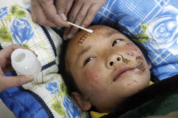 Ten-year-old Cewn Degyi(R) is treated by mediciner in an aircraft heading to Xining for treat in Yushu, northwest China's Qinghai Province, April 19, 2010. Civil aircrafts and military planes were put into operation for rescue team and supply transportation after the quake hit Yushu County.