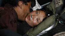Cering Wangde (L) comforts his wife in an aircraft heading to Xining for treat in Yushu, northwest China's Qinghai Province, April 19, 2010.