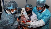 Nurses hold a newborn baby at a makeshift shelter in Yushu County, northwest China's Qinghai Province, on April 19, 2010.
