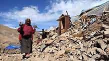 A local resident of China's Tibetan Ethnic Group turns the prayer wheel as she passes by debris in the quake-hit Gyegu Town of Yushu County, northwest China's Qinghai Province, April 20, 2010.