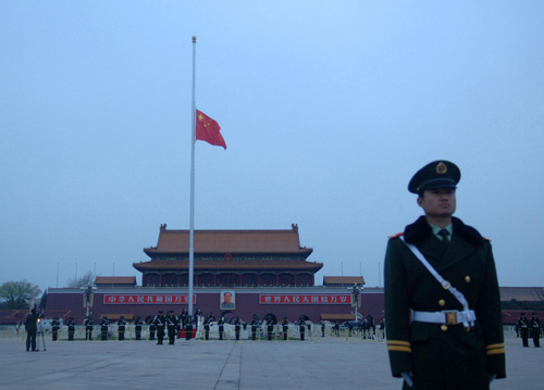 A paramilitary policeman stands guard while the national flag flies at half-mast on Tiananmen Square in Beijing, April 21, 2010. The State Council, China's cabinet, announced a national day of mourning would be held on Wednesday for the quake victims.