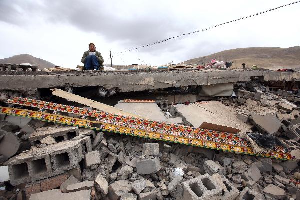 A boy reads a book borrowed from his neighbour on his ruined house on April 21, 2010.It has been more than a week since a devastating earthquake hit Yushu, northwestern China's Qinghai province on April 14, 2010. 
