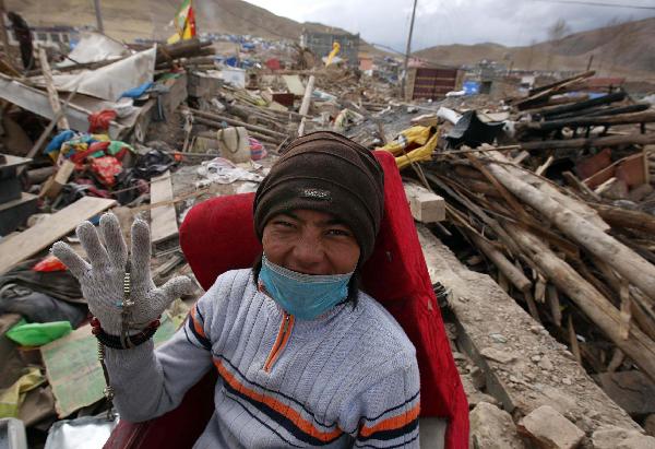 A young man is collecting useful daily items buried in his ruined house and jokes to the photographer that he hopes his wife will give birth to five children for him in the future.It has been more than a week since a devastating earthquake hit Yushu, northwestern China's Qinghai province on April 14, 2010. 