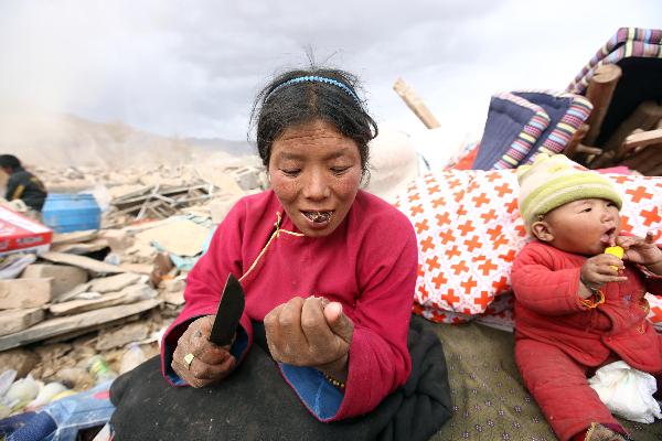 A woman is eating mutton by her ruined house. She lost two kids in the earthquake and wished to bear another two in the future. It has been more than a week since a devastating earthquake hit Yushu, northwestern China's Qinghai province on April 14, 2010.