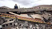 A boy reads a book borrowed from his neighbour on his ruined house on April 21, 2010.It has been more than a week since a devastating earthquake hit Yushu, northwestern China's Qinghai province on April 14, 2010.