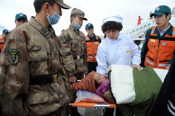 Rescuers carry an injured to an aircraft at an airport in quake-hit Yushu County, northwest China&apos;s Qinghai Province, April 22, 2010. 
