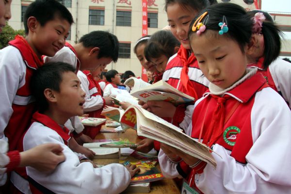 A girl selects books in a charity bazaar on campus of Jianshelu Elementary School, in Zaozhuang City, east China's Shandong Province, April 22, 2010. 