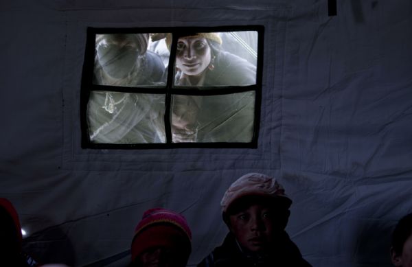 Parents watch their kids having classes at a tent school in Longbao Town of the quake-hit Tibetan Autonomous Prefecture of Yushu, northwest China's Qinghai Province, April 22, 2010. A total of 48 tends have been set up for 847 students and 39 teachers before 9:00 PMof April 21 and students began school on the morning of April 22 . 