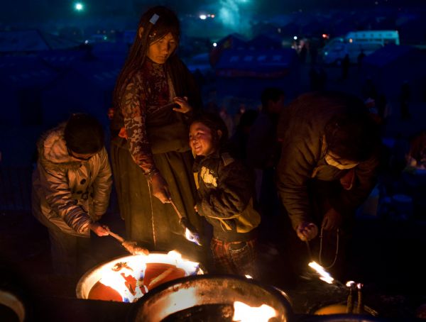 People of Tibetan ethnic group and her family light lamps at a racecourse in quake-hit Tibetan Autonomous Prefecture of Yushu, northwest China's Qinghai Province, April 24, 2010. 