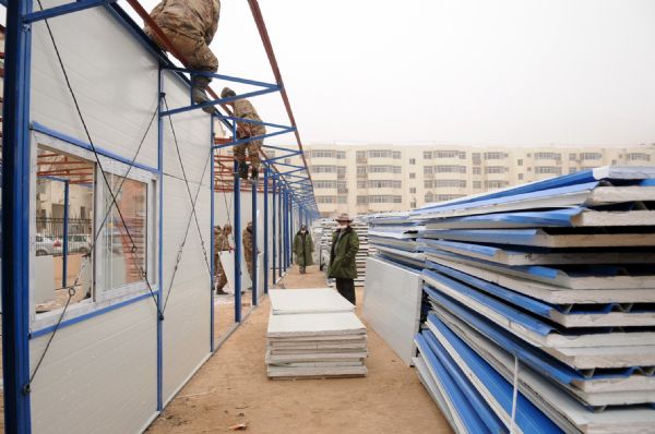 Workers build prefab houses in Jiegu town of quake-hit Tibetan Autonomous Prefecture of Yushu, northwest China's Qinghai Province, April 25, 2010. Several companies started to build prefab houses in Yushu and the program will be finished within one month. 