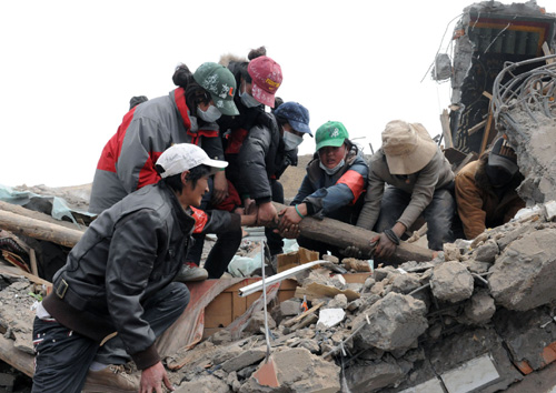 Volunteers clean up house debris in Yushu, Northwest China's Qinghai Province on April 21, 2010.