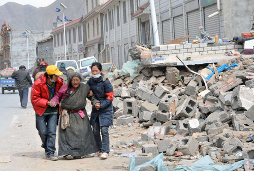 Two volunteers manage to persuade an old woman who refused to leave her collapsed house to stay in a tent in Yushu, Northwest China's Qinghai Province on April 21, 2010.