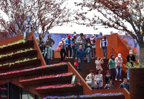 Visitors walk out of the Luxemburg Pavilion decorated by flowers and bushes April 25, 2010. [
