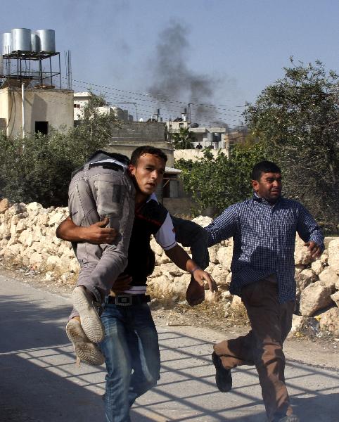 A Palestinian carries a wounded protester during clashes with Israeli soldiers, in the West Bank village of Beit Awwa, near Hebron April 26, 2010. 