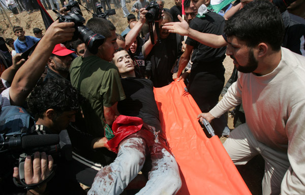 Palestinian protesters carry a wounded man during a demonstration against the Israeli no-go zone on the eastern outskirts of Gaza city on April 28, 2010.