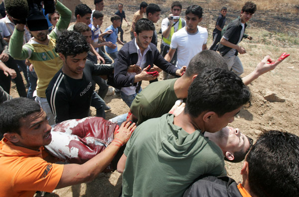 Palestinian protesters carry a wounded man during a demonstration against the Israeli no-go zone on the eastern outskirts of Gaza city on April 28, 2010.