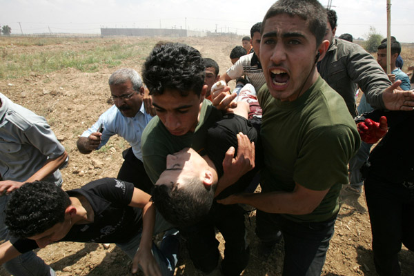 Palestinian protesters carry a wounded man during a demonstration against the Israeli no-go zone on the eastern outskirts of Gaza city on April 28, 2010.