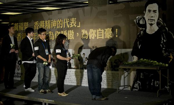 Attendees present flowers to the photo of Wong Fu-wing during a memorial service to honor Wong Fu-wing, a volunteer from Hong Kong who lost his life when rescuing others during the Yushu quake in southwest China's Qinghai Province, in Hong Kong, south China, April 28, 2010.