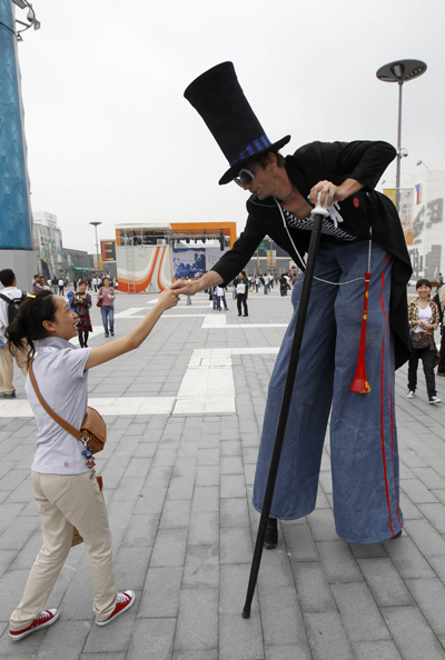 A tourist shakes hands with a stilt actor in the World Expo Park in Shanghai, east China, on May 5, 2010.