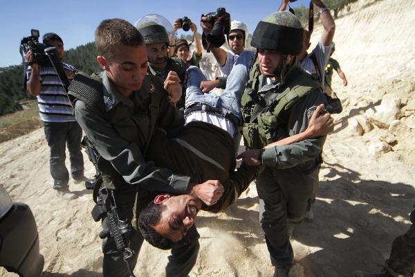 Israeli soldiers detain a protester during a demonstration by Palestinian and foreign peace activists against Israel&apos;s controversial separation barrier in the West Bank village of Walajeh, near Bethlehem, May 6, 2010. 