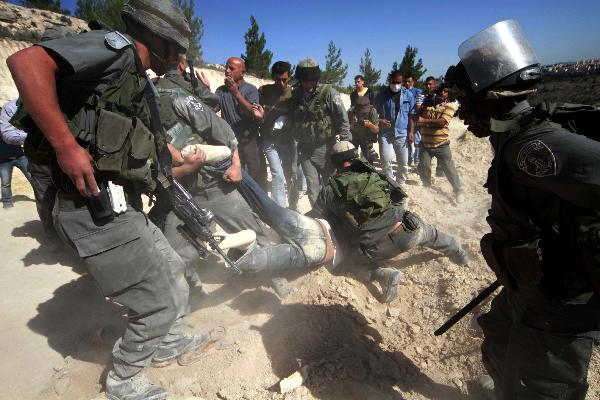 Israeli soldiers detain a protester during a demonstration by Palestinian and foreign peace activists against Israel&apos;s controversial separation barrier in the West Bank village of Walajeh, near Bethlehem, May 6, 2010. 