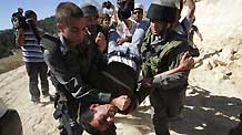 Israeli soldiers detain a protester during a demonstration by Palestinian and foreign peace activists against Israel's controversial separation barrier in the West Bank village of Walajeh, near Bethlehem, May 6, 2010.