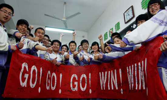 Students gesture after they sign their names on a banner to cheer up for the intensive preparation for the national college entrance examination at a high school in Jinan, East China's Shandong Province, May 6, 2010. The annual national college entrance examination, known as the gaokao, will be held for three days on June 7, 8 and 9. 