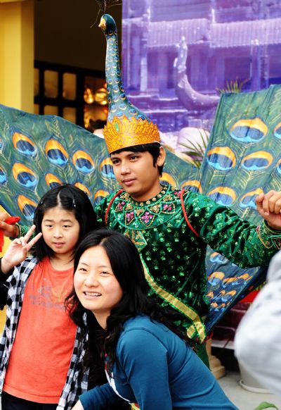 Visitors pose for a group photo with an actor dressed as a peacock of the Cambodia Pavilion at the World Expo Park in Shanghai, east China, May 8, 2010. 