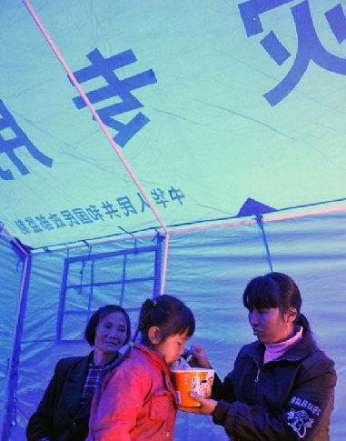 A woman feeds her child with noodles in a tent in Fengjia Township of Xinhua County, central China&apos;s Hunan Province, May 7, 2010. Heavy rain from Wednesday night in some parts of Hunan Province has triggered geological accidents, including landslides and mud flows and left 10 people dead and three missing as of Friday noon.
