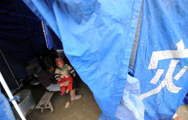 A woman holding her child in arms rests in a tent in Fengjia Township of Xinhua County, central China&apos;s Hunan Province, May 7, 2010. Heavy rain from Wednesday night in some parts of Hunan Province has triggered geological accidents, including landslides and mud flows and left 10 people dead and three missing as of Friday noon.
