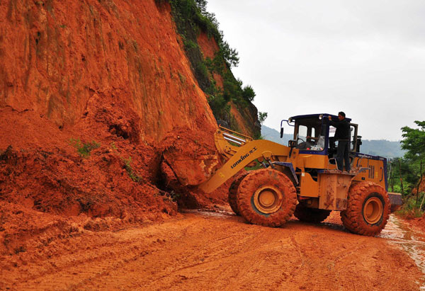A bulldozer clears the road blocked due to landslide in Dafeng Village, Egong Town of Dingnan County in east China&apos;s Jiangxi Province, May 7, 2010. Seven people were dead and five were missing after floods and landslides wreaked havoc in Jiangxi over the past two days.