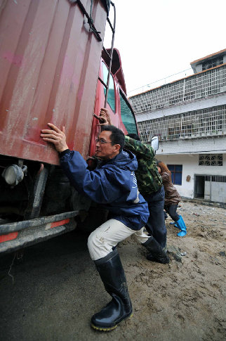 People help pull out a truck delivering relief materials which is trapped in the mud in Fengjia Township of Xinhua County, central China&apos;s Hunan Province, May 7, 2010. Heavy rain from Wednesday night in some parts of Hunan Province has triggered geological accidents, including landslides and mud flows and left 10 people dead and three missing as of Friday noon.