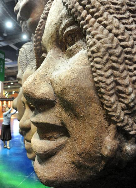 A girl has a picture taken in front of a wall with sculptures of smilling faces inside the United African Pavilion at the 2010 World Expo site in Shanghai May 9, 2010.