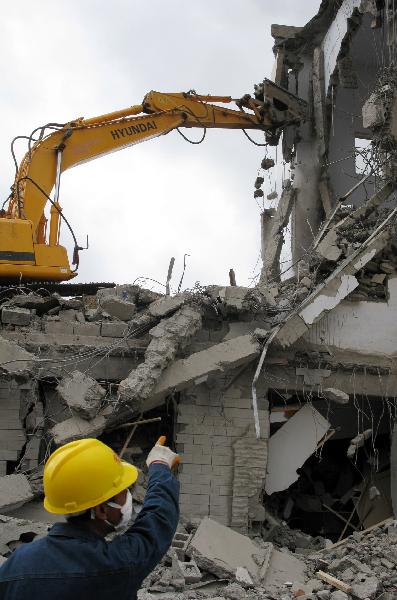 An excavator works at a building destroyed in the quake in Jiegu Town, Yushu Tibetan Autonomous Prefecture of northwest China's Qinghai Province, May 10, 2010. 