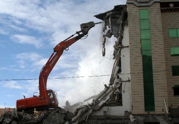 An excavator works at a building destroyed in the quake in Jiegu Town, Yushu Tibetan Autonomous Prefecture of northwest China's Qinghai Province, May 10, 2010. 
