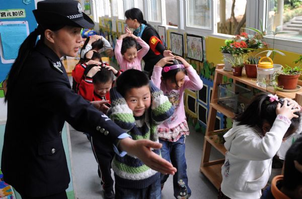 Children guided by a policewoman and a teacher escape from a building during a drilling in Nanjing experimental kindergarten in Nanjing, capital of east China's Jiangsu Province, May 10, 2010. The drilling was held Monday in Nanjing, aiming at teaching children to escape from buildings and to protect themselves when earthquake happens.