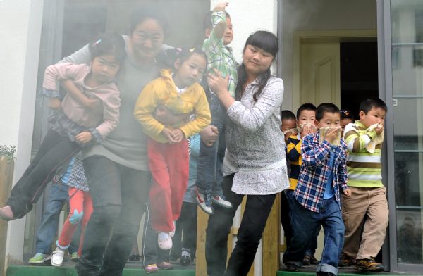 Children guided by teachers escape from a building during a drilling in Nanjing experimental kindergarten in Nanjing, capital of east China's Jiangsu Province, May 10, 2010. 