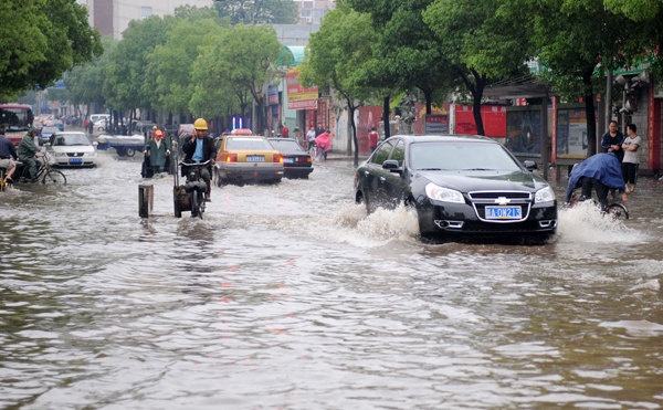 Vehicles run on a flooded street in Nanchang, capital of east China's Jiangxi Province, on May 8, 2010. Heavy rain hit Nanchang on Saturday and caused flood in the city.