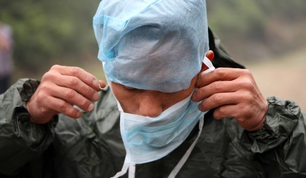 A staff member of the government's epidemic prevention department prepares to work after a flood in Zhuxi village of Xupu County in Huaihua City, central China's Hunan Province, May 16, 2010. 