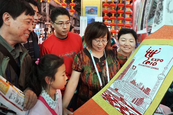 Craftman Zhou Shuying (2nd R) displays a piece of paper-cut work with the theme of World Expo in Shanghai of China, May 16, 2010. 