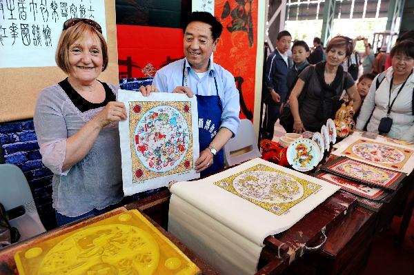 Craftman Liu Guosheng (2nd L) sends a piece of Wuqiang new-year painting, a kind of wood engraving painting from northern China's Hebei Province, in Shanghai of China, May 16, 2010.