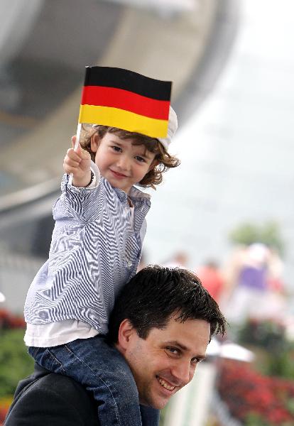 A child, sitting on the shoulders of an adult, waves German national flag as they participate in the celebration marking the National Pavilion Day for Germany at the World Expo park in Shanghai, May 19, 2010. 