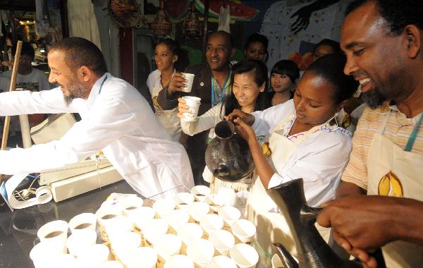 Shanghai citizen Zhang Gennan (R3, front), the 1 millionth visitor to the Africa Joint Pavilion, tastes coffee in the Ethiopia Pavilion in World Expo park in Shanghai, May 19, 2010. Visitors to the Africa Joint Pavilion reached 1 million Wednesday. 