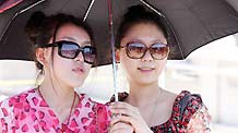 Two girls with parasol pose for photos at the Tian'anmen Square in Beijing, capital of China, May 19, 2010. A heat wave hit some areas of China recently.